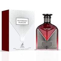 Maison Alhambra Victorioso Fearless — Botol minyak wangi kaca merah faset dengan aksen perak dan penutup hitam, bersebelahan kotak corak geometri putih dan merahnya.