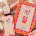 Lattafa Ajwad Pink 2 Pink Creamy Elixir — Botol dan kotak minyak wangi corak pastel berombak, perincian emas, dan elemen bunga.