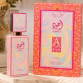 Lattafa Ajwad Pink 2 Pink Creamy Elixir — Botol minyak wangi merah jambu dan kotak sepadan dengan corak berombak berwarna-warni dan kaligrafi Arab.