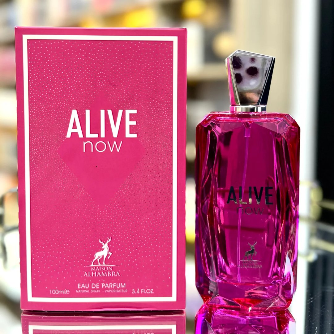 Maison Alhambra Alive Now — A bright pink box with white text and a deer logo sits next to a faceted pink glass perfume bottle with a silver cap. | Maison Alhambra Alive Now — Kotak merah jambu terang dengan teks putih dan logo rusa duduk di sebelah botol minyak wangi kaca merah jambu berfaset dengan penutup perak.