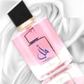 Ard Al Zaafaran Amal Ard Al Zaafaran 100ml Women — Botol minyak wangi merah jambu dengan perincian emas dan penutup hitam, diletakkan di atas fabrik satin putih.