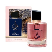 Ard Al Zaafaran Amal Ard Al Zaafaran 100ml Wanita — Botol minyak wangi merah jambu dengan perincian emas dan kaligrafi Arab, bersebelahan kotak merah jambu dan birunya dengan rekaan abstrak emas.