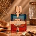 French Avenue Aromatix Teas Me 100ml — A gradient glass perfume bottle with blue and red hues, featuring a gold cap and a gold band with the "AROMATIX FRENCH AVENUE" logo, set against a soft, warm background with dried flowers and a silk cloth.