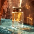 Lattafa Atlas Canyon 55ml Unisex — Botol minyak wangi kaca jernih berisi cecair keemasan, berdiri dalam air biru kehijauan yang mengalir dengan latar belakang ngarai.