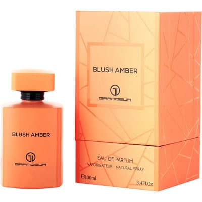 Grandeur Blush Amber 100ml — A perfume box and bottle in orange hues with geometric patterns. The box is on the left, and the bottle is on the right. | Grandeur Blush Amber 100ml — Kotak dan botol minyak wangi dalam rona jingga dengan corak geometri. Kotak berada di sebelah kiri, dan botol berada di sebelah kanan.