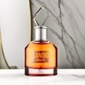Maison Alhambra Candid Tonight by Maison Alhambra 100ml — A clear glass perfume bottle with orange liquid and a diamond-shaped clear cap, set against a marble-patterned background. | Maison Alhambra Candid Tonight by Maison Alhambra 100ml — Botol kaca jernih berisi cecair oren dan penutup berbentuk berlian jernih