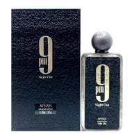 Afnan 9 PM Night Out Extrait de Parfum — A dark textured box stands next to a clear glass perfume bottle with a textured dark label and a grey spherical cap. | Afnan 9 PM Night Out Extrait de Parfum — Kotak bertekstur gelap berdiri di sebelah botol minyak wangi kaca jernih dengan label gelap bertekstur dan penutup