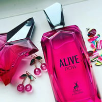 Maison Alhambra Alive Now by Maison Alhambra 100ml — Two pink geometric perfume bottles with silver caps, one star-shaped, and cherry-shaped earrings with green leaves, next to colorful abstract earrings. | Maison Alhambra Alive Now by Maison Alhambra 100ml — Dua botol minyak wangi merah jambu geometri dengan penutup