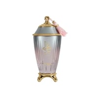 Zimaya Ghali Elegant Eau De Parfum 100ml by Zimaya — A tall, fluted glass perfume bottle with a gradient pink and silver finish, topped with a gold and grey textured cap adorned with a pink tassel. The bottle stands on a gold ornate base. | Zimaya Ghali Elegant Eau De Parfum 100ml by Zimaya — Botol kaca tinggi