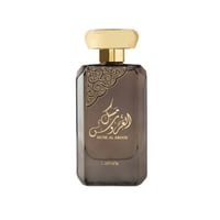 Lattafa Musk Al Aroos — A rectangular, dark brown glass perfume bottle with a gold cap and ornate gold Arabic calligraphy on the front. | Lattafa Musk Al Aroos — Botol kaca berwarna coklat gelap berbentuk segi empat dengan penutup emas dan kaligrafi Arab emas yang berhias di bahagian hadapan.