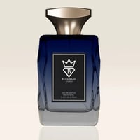 Bujairami New York by Bujairami Eau de Parfum 100ml — A blue and grey gradient glass perfume bottle with a gold cap and a black label featuring a white crown and 'B' logo.