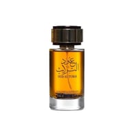 Ard Al Zaafaran Oud Al Turas 100ml by Ard Al Zaafaran — A clear glass perfume bottle with golden liquid and Arabic calligraphy on the label, topped with a textured gold cap. | Ard Al Zaafaran Oud Al Turas 100ml by Ard Al Zaafaran — Botol minyak wangi kaca jernih dengan cecair keemasan dan kaligrafi Arab pada label, di