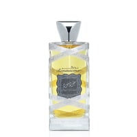 Lattafa Oud Mood Reminiscence — Botol minyak wangi kaca jernih berisi cecair kuning, dibalut reben putih bertulis 'Oud Mood', penutup perak, label kelabu gelap berserta tulisan Arab dan teks 'Oud Mood Reminiscence'.