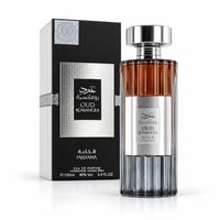 Ard Al Zaafaran Oud Romancea Fakhama 100ml Unisex — A clear glass perfume bottle with ribbed sides and amber liquid, topped with a silver cap, stands next to its black and silver textured box.