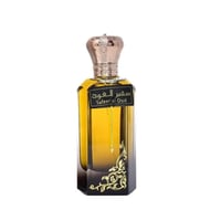 Ard Al Zaafaran Safeer Al Oud — Amber liquid in a clear glass bottle with a gold crown cap and ornate gold detailing on the