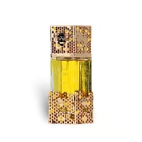 Lattafa Atheeri by Lattafa – 100 ml for Women - botol wangian emas dengan reka bentuk sarang lebah dan lebah di bahagian atas, cecair kuning terang di dalam, latar belakang putih.