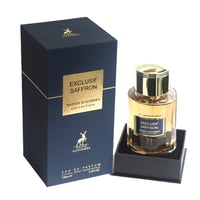 Maison Alhambra Exclusif Saffron — Navy blue box with gold accents and a clear glass perfume bottle with gold cap and amber liquid, presented on a black stand.