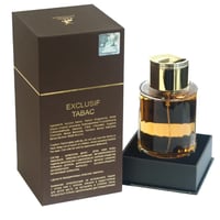 Maison Alhambra Exclusif Tabac — Brown box with gold trim and bottle of amber fragrance with gold cap, set on a black display stand.