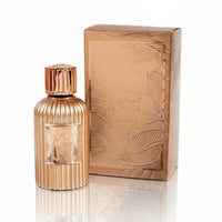 Paris Corner Qissa Delicious by Paris Corner – 100 ml for Women, a gold fluted perfume bottle with a ribbed rose gold cap stands next to its matching embossed gold box with leaf patterns.
