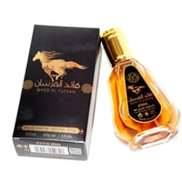 Ard Al Zaafaran Qaed Al Fursan — Black perfume box with a golden horse silhouette and Arabic script, next to a golden-capped glass perfume bottle filled with amber liquid. | Kotak minyak wangi hitam dengan siluet kuda keemasan dan tulisan Arab, bersebelahan dengan botol minyak wangi kaca bertudung emas berisi cecair