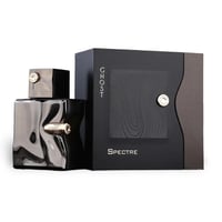French Avenue Ghost Spectre — A dark, metallic, bullet-shaped perfume bottle with a black box featuring a wood grain pattern and a silver emblem. | French Avenue Ghost Spectre — Botol minyak wangi gelap, metalik, berbentuk peluru dengan kotak hitam menampilkan corak bijirin kayu dan lambang perak.