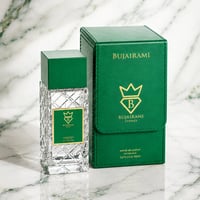 Bujairami Vibration by Bujairami 100ml Extrait de Parfum — Clear faceted glass perfume bottle with green cap and gold label, next to a matching green presentation box with gold logo and text, on a marble background.