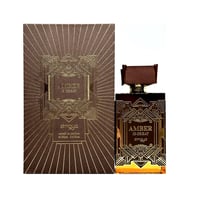 Zimaya Amber Is Great Eau De Parfum 100ml — A brown textured box with gold geometric art deco design stands next to a rectangular glass perfume bottle with a ribbed brown cap and gold geometric art deco design. The bottle contains amber-colored liquid. | Zimaya Amber Is Great Eau De Parfum 100ml — Kotak bertekstur