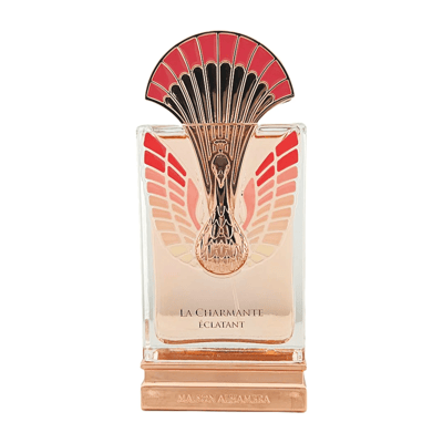 Maison Alhambra La Charmante Eclatant — Clear glass perfume bottle with rose gold base, featuring a decorative peacock-like gold and red fan-shaped cap and wing motifs on the bottle.
