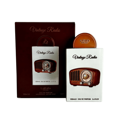 Lattafa Pride Vintage Radio — Two perfume boxes, one dark brown and one white, with a vintage radio illustration. The dark brown box is larger and partially open, revealing a smaller white box inside. A gold cap is placed on top of the white box.