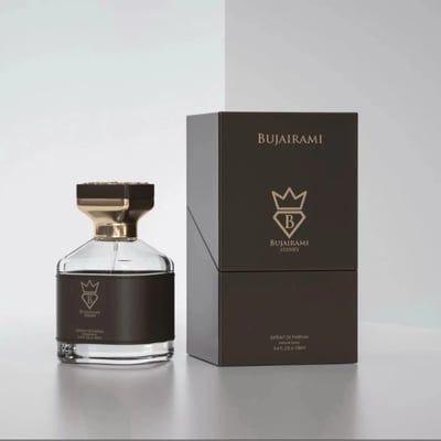 Bujairami Kingsman by Bujairami 100ml Extrait de Parfum — Clear glass perfume bottle with dark brown leather accent and gold cap, next to its matching dark brown presentation box with gold logo.