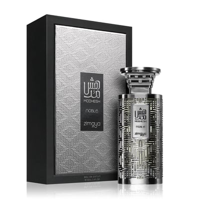 Zimaya Modhesh Noble 100ml — A silver patterned box stands next to a matching silver patterned perfume bottle, both with Arabic script and text. | Zimaya Modhesh Noble 100ml — Kotak corak perak berdiri di sebelah botol minyak wangi corak sepadan, kedua-duanya dengan skrip Arab dan teks.
