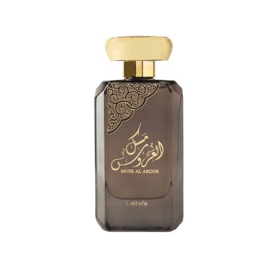 Lattafa Musk Al Aroos — A rectangular, dark brown glass perfume bottle with a gold cap and ornate gold Arabic calligraphy on the front. | Lattafa Musk Al Aroos — Botol kaca berwarna coklat gelap berbentuk segi empat dengan penutup emas dan kaligrafi Arab emas yang berhias di bahagian hadapan.