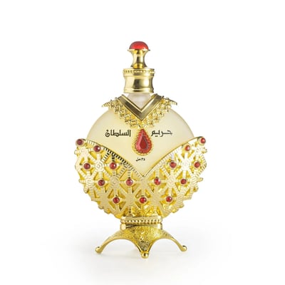 Khadlaj Hareem Al Sultan Gold by Khadlaj 35ml — Ornate gold perfume bottle with red gem accents and Arabic calligraphy, presented on a decorative gold stand.