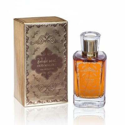 Nafahat Oud Maluky by Nafahat 100ml Unisex — A golden-brown glass perfume bottle with ornate gold detailing sits next to its matching textured golden box, both on a reflective white surface.
