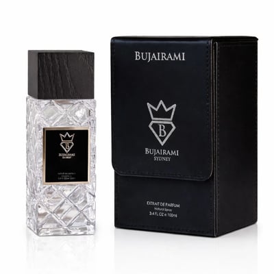 Bujairami Shadow Script - Bujairami 100ml Extrait — Clear faceted glass perfume bottle with a black wooden cap next to a black textured presentation box with silver branding.