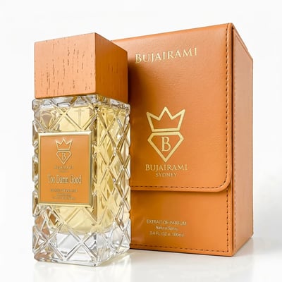 Bujairami Too Damn Good — Clear glass perfume bottle with a textured diamond pattern, a wooden cap, and an orange label. An orange leather-like box with gold branding is positioned behind it.