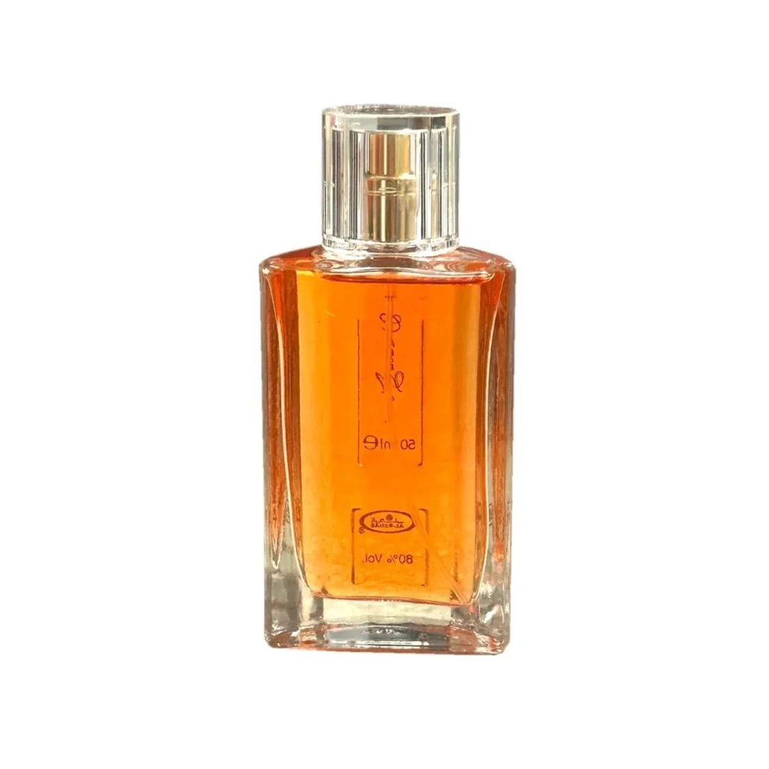 Al Rehab Choco Musk by Al Rehab 50ml EDP Unisex — A clear glass perfume bottle with amber liquid, a clear faceted cap, and red text labels on the front. | Al Rehab Choco Musk by Al Rehab 50ml EDP Unisex — Botol minyak wangi kaca jernih berisi cecair berwarna ambar, penutup faset jernih, dan label teks merah di