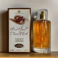 Al Rehab Choco Musk by Al Rehab 50ml EDP Unisex — A box of Choco Musk perfume sits next to its glass bottle, both on a wooden surface. The box has Arabic script and floral graphics. | Al Rehab Choco Musk by Al Rehab 50ml EDP Unisex — Sekotak minyak wangi Choco Musk terletak di sebelah botol kaca, kedua-duanya di atas