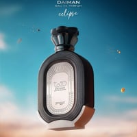 Zimaya Daiman Eclipse Eau De Parfum — A dark, textured perfume bottle with a silver emblem sits against a bright blue sky with scattered golden particles and clouds. | Zimaya Daiman Eclipse Eau De Parfum — Botol minyak wangi gelap bertekstur dengan lambang perak diletakkan berlatar belakang langit biru terang dengan