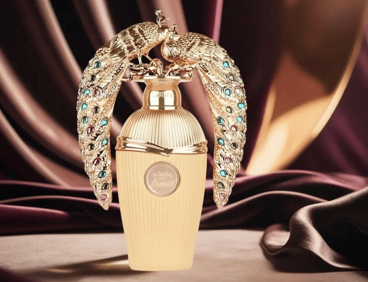 Lattafa Afeef by Lattafa 100ml EDP — A gold-colored perfume bottle with a decorative gold peacock cap adorned with colorful gems, set against a draped dark fabric background.