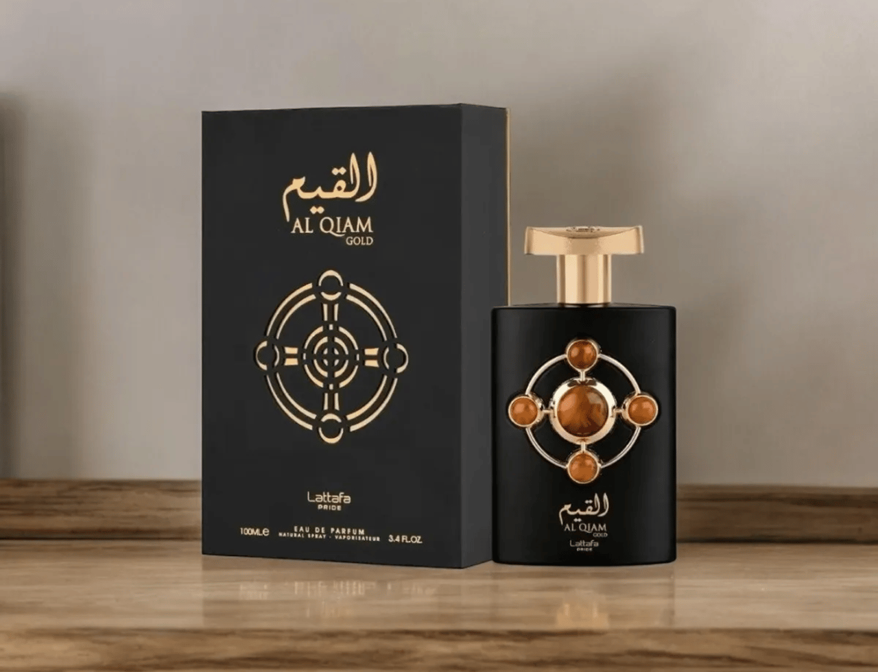 Lattafa Pride Al Qiam Gold EDP 100ml — Black perfume bottle with gold cap and amber stone accents, next to its matching black and gold box on a wooden surface.