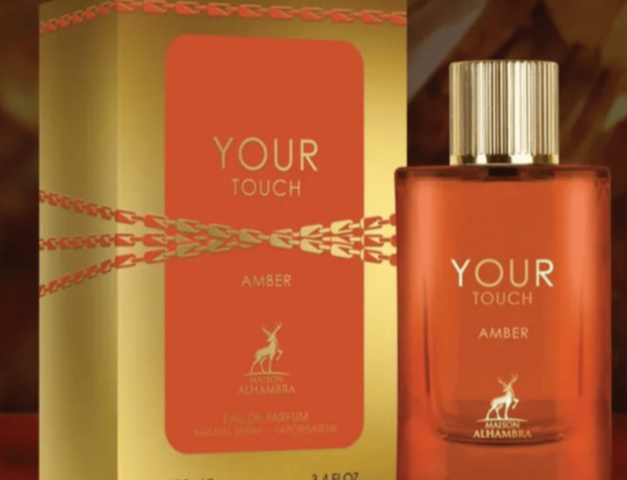Maison Alhambra Your Touch Amber — Gold box with orange label and chain design next to an amber glass perfume bottle with a gold cap.