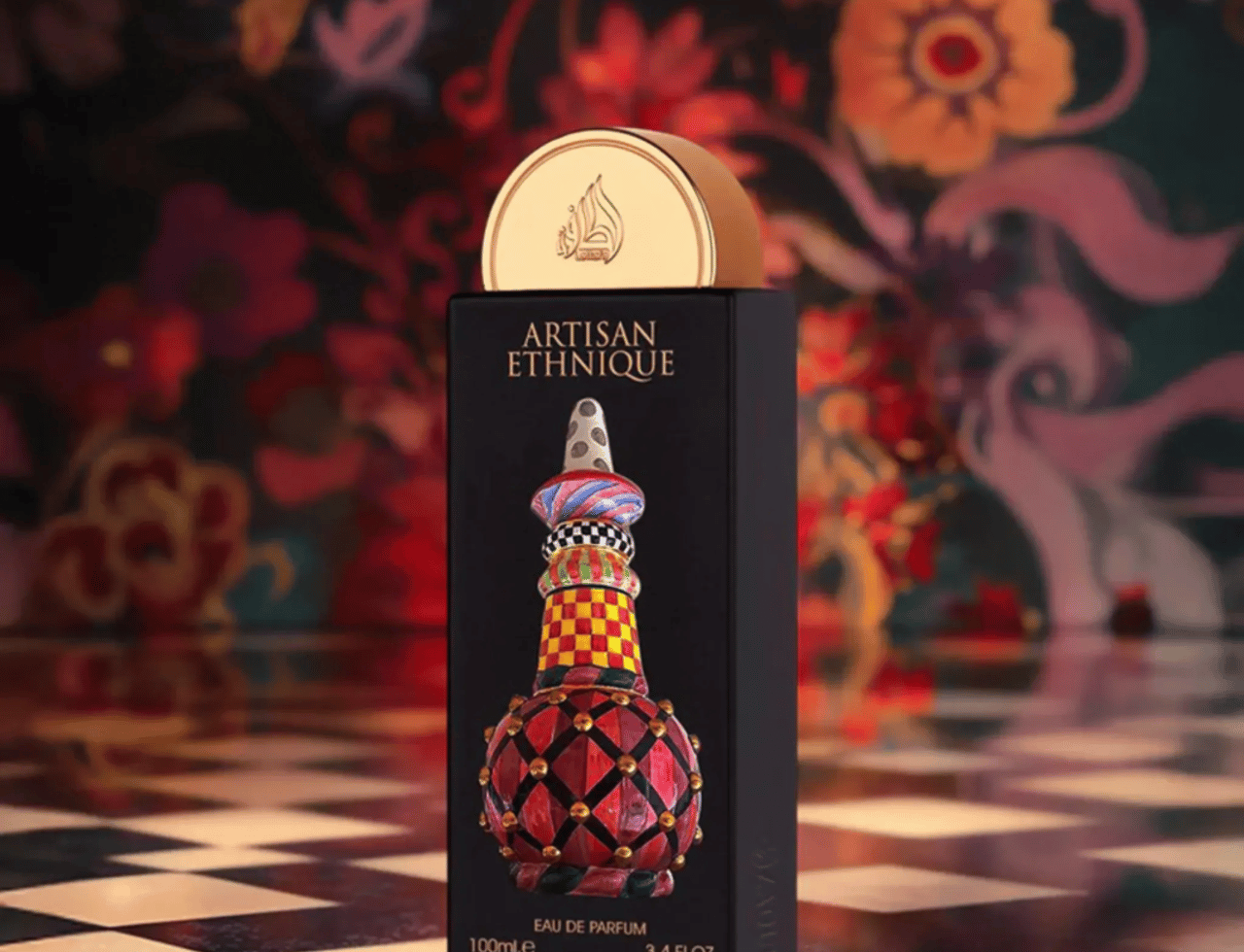 Lattafa Pride Artisan Ethnique by Lattafa Pride 100ml EDP — Kotak hitam dengan rekaan botol berwarna-warni yang berhias, penutup emas, di atas permukaan berpetak dengan latar belakang corak bunga.