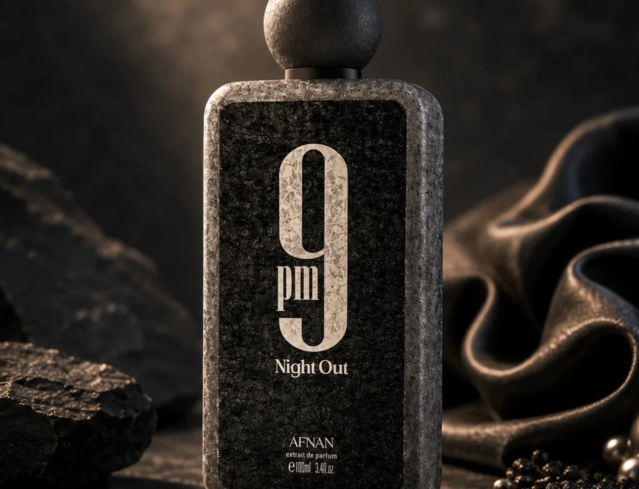 Afnan 9 PM Night Out Extrait de Parfum — Botol minyak wangi kelabu berbatu dengan penutup bulat kelabu gelap, tertulis '9 pm Night Out' dan 'AFNAN' di bahagian bawah, di atas meja marmar gelap dengan batu kelabu dan kain satin hitam beralun di latar belakang.