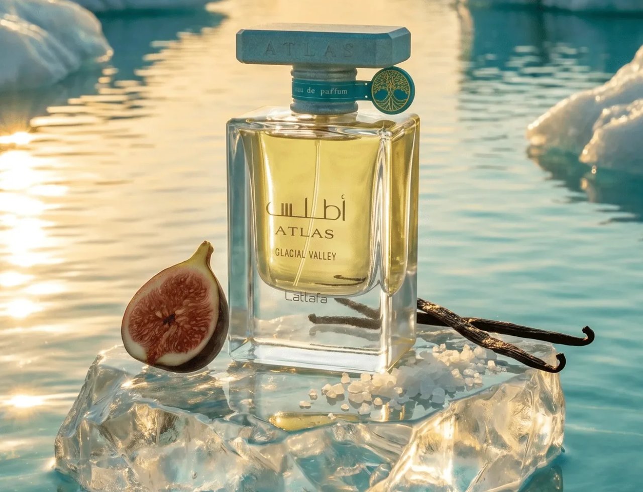 Lattafa Atlas Glacial Valley by Lattafa 55ml Unisex — Botol minyak wangi kaca jernih berisi cecair kuning muda, bertutup biru, diletakkan di atas bongkah ais. Sebiji buah tin terbelah, batang vanila, dan habluran garam mengelilingi botol. Latar belakang menampilkan formasi ais dan air tenang memantulkan cahaya