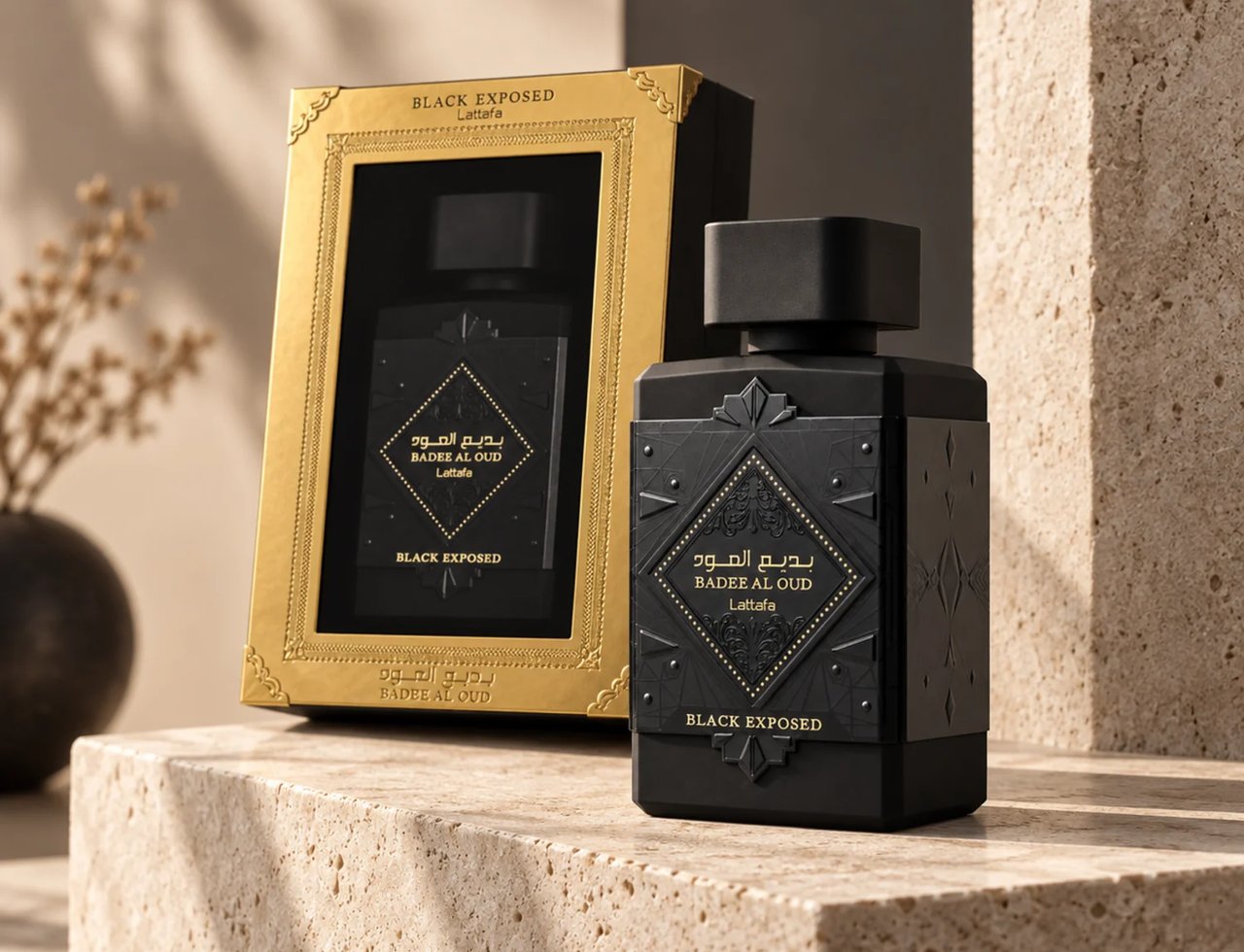 Lattafa Bade'e Al Oud Black Exposed Lattafa 100ml — Black perfume bottle and its gold-trimmed gift box displayed on textured stone surfaces, with a blurred dried plant in the background.
