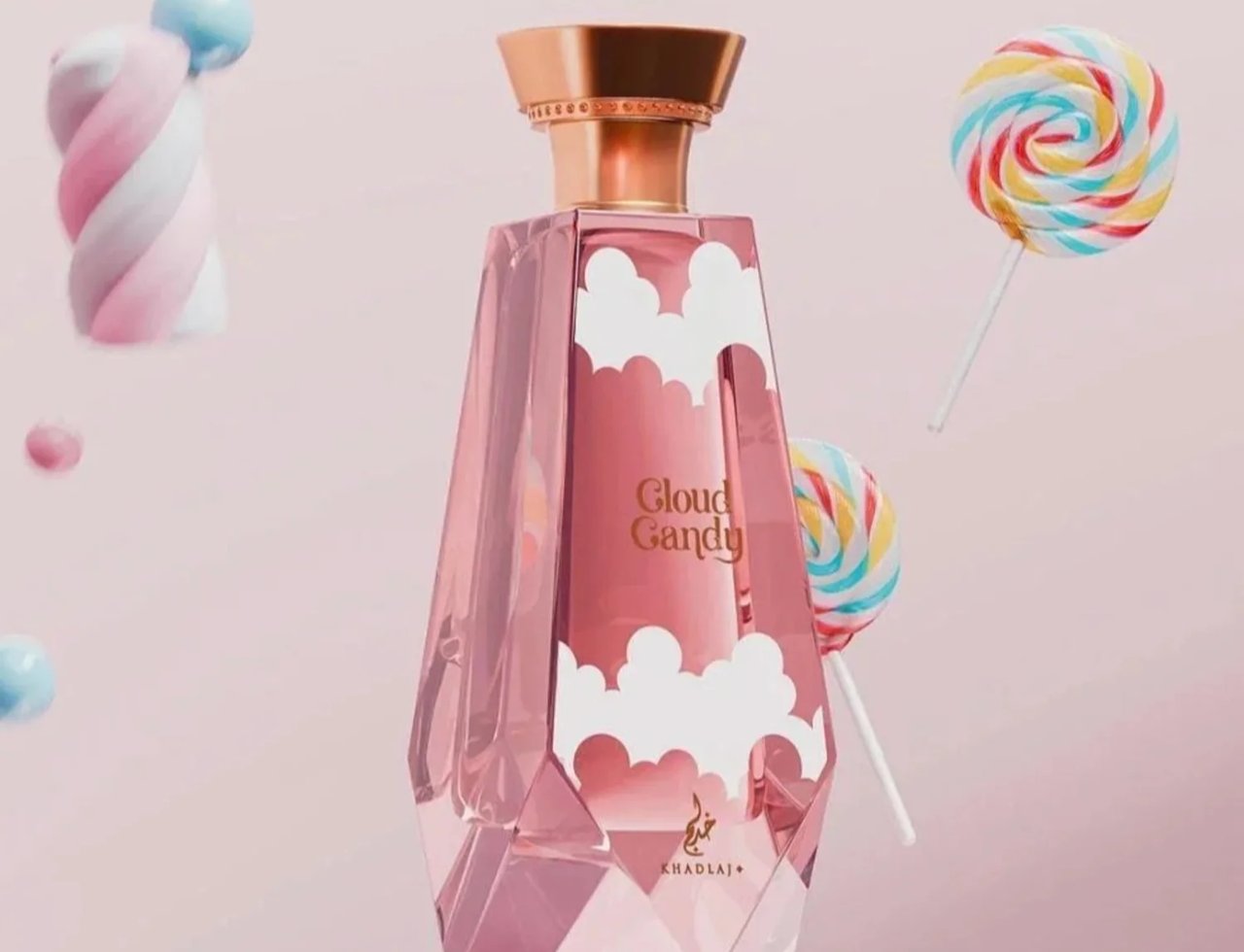 Khadlaj Cloud Candy Eau De Parfum — Botol wangian merah jambu berbentuk berlian dengan awan putih, dihiasi dengan lolipop berwarna-warni dan marshmallow terapung di latar belakang merah jambu.