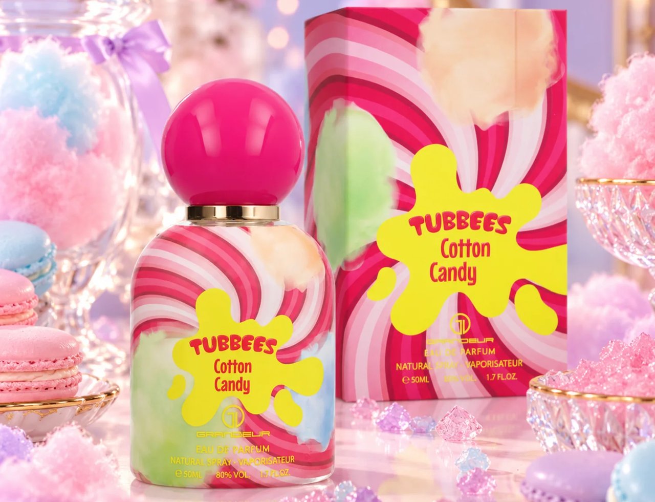Grandeur Cotton Candy by Tubbees 50ml EDP Unisex — Botol minyak wangi berpenutup merah jambu dengan rekaan kapas gula berpusar merah jambu, putih dan pastel, bersebelahan kotak padanannya. Makaron dan ketulan gula kristal mengelilingi paparan.