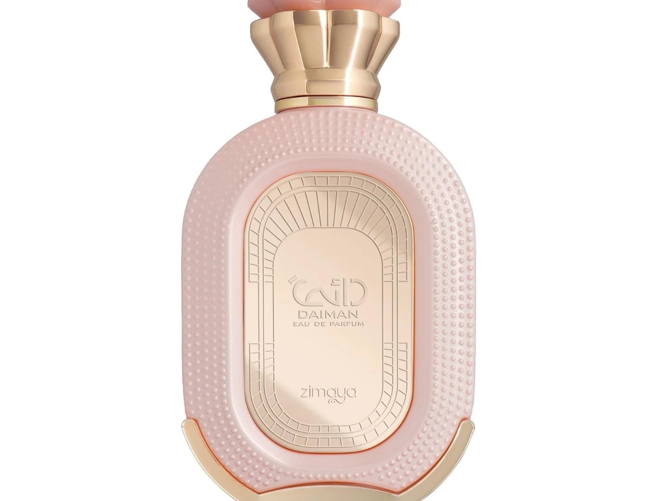 Zimaya Daiman Eden Eau De Parfum 100ml — A light pink oval perfume bottle with a textured surface and gold accents, featuring a gold embossed label with Arabic script and text. The cap is a pale pink, flower-like design with a gold base. | Zimaya Daiman Eden Eau De Parfum 100ml — Botol minyak wangi bujur berwarna