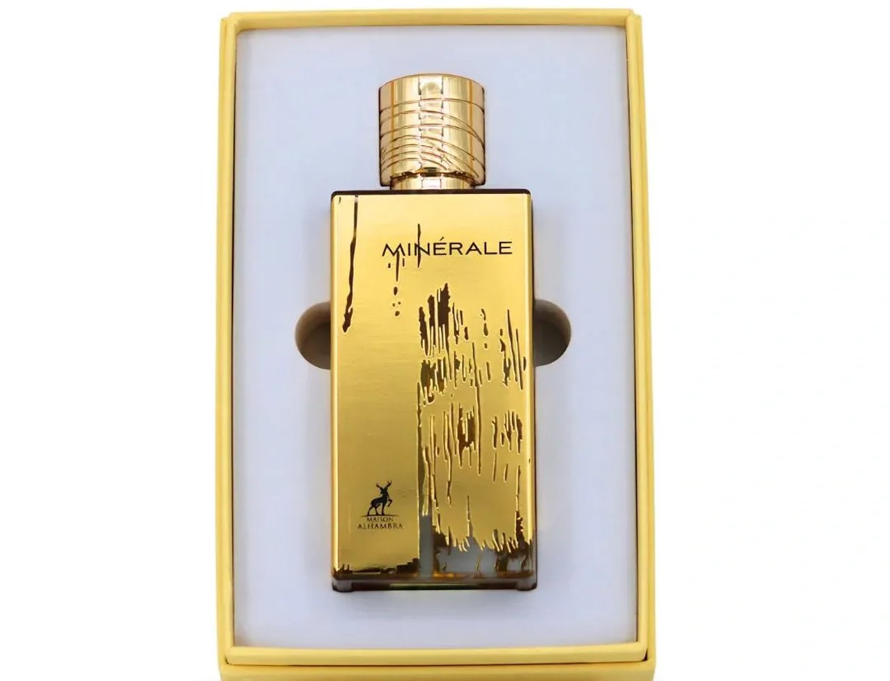 Maison Alhambra Minerale Gold by Maison Alhambra 100ml EDP — Botol minyak wangi tona emas dengan penutup bertekstur, diperagakan dalam kotak hadiah kuning dengan sisipan putih.